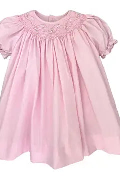 Pink dress with smocked details on a white background