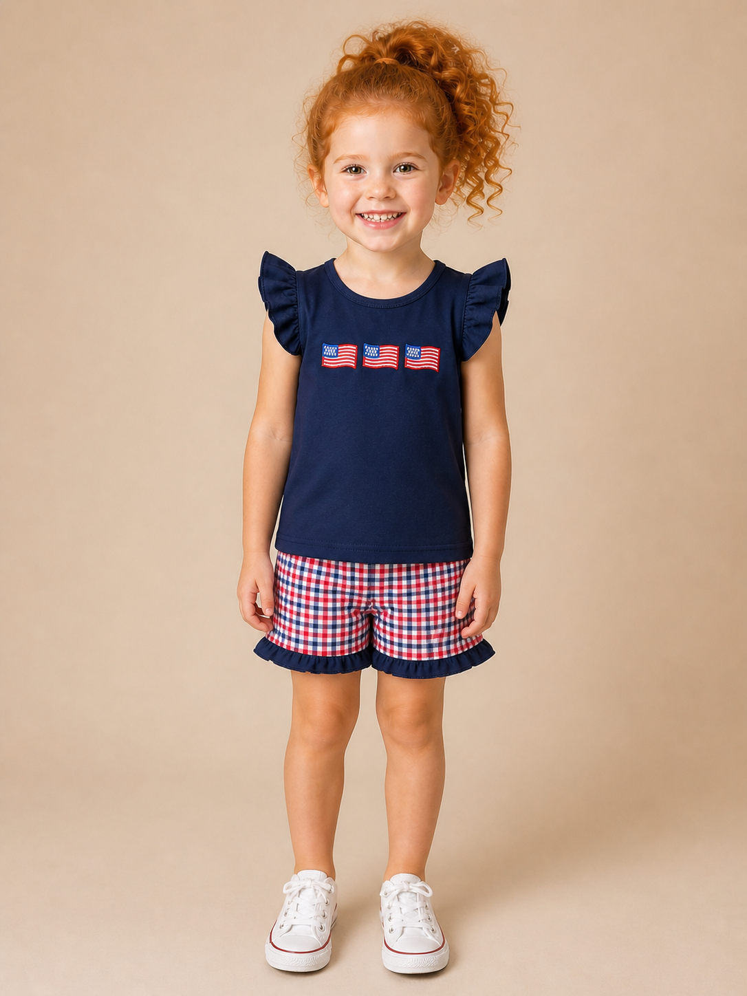 Red hair girl with navy shirt with flags on the front and plaid shorts.