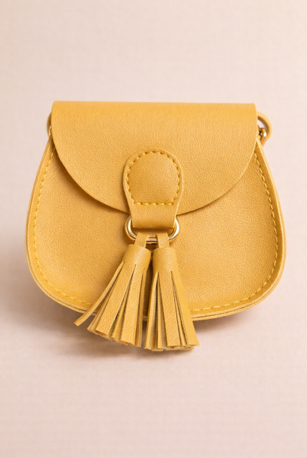 Yellow handbag with a tassel on a beige background