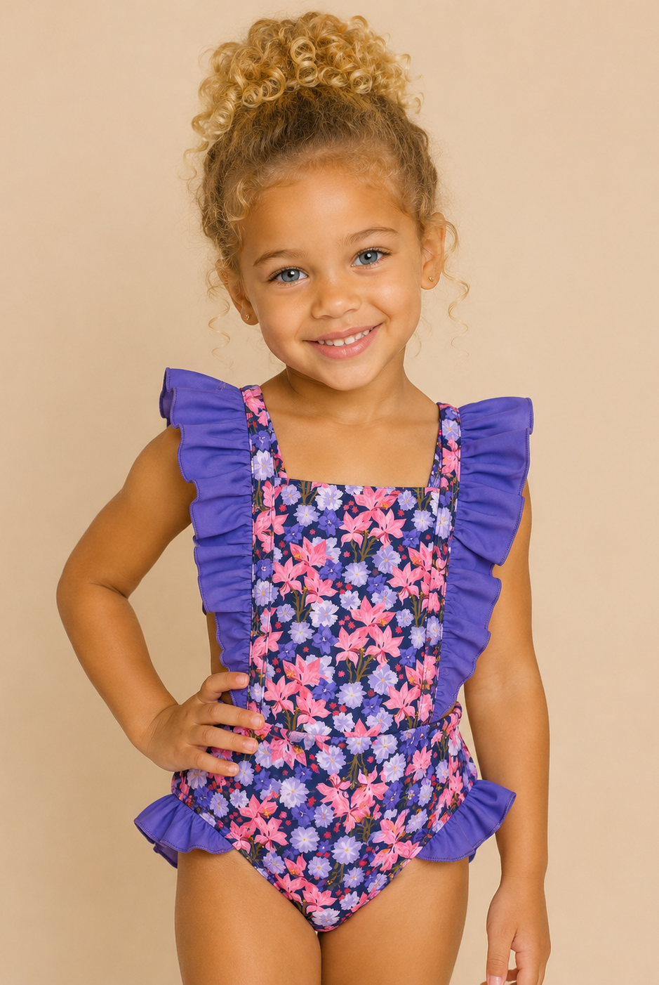 Child wearing a floral swimsuit with purple ruffles on a beige background