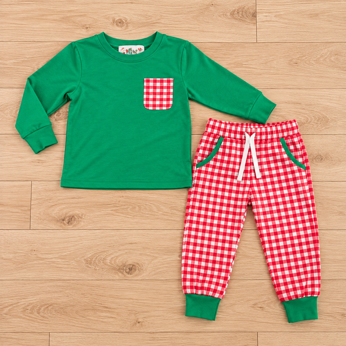 Green boys’ long-sleeve top with a red-and-white gingham chest pocket beside matching gingham jogger pants with green cuffs and a white waist tie.