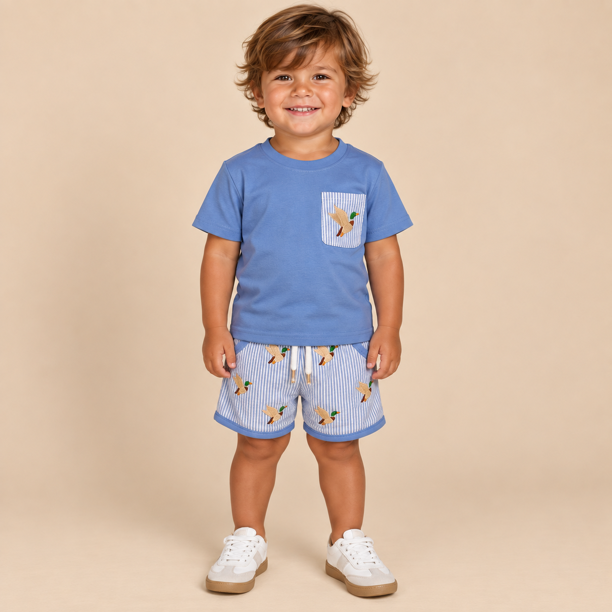 Toddler boy wearing a light blue t shirt with a mallard duck on the pocket with matching seersucker shorts.