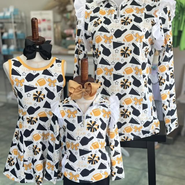 Children's clothing set with dresses and a jacket on mannequins against a blurred store background.