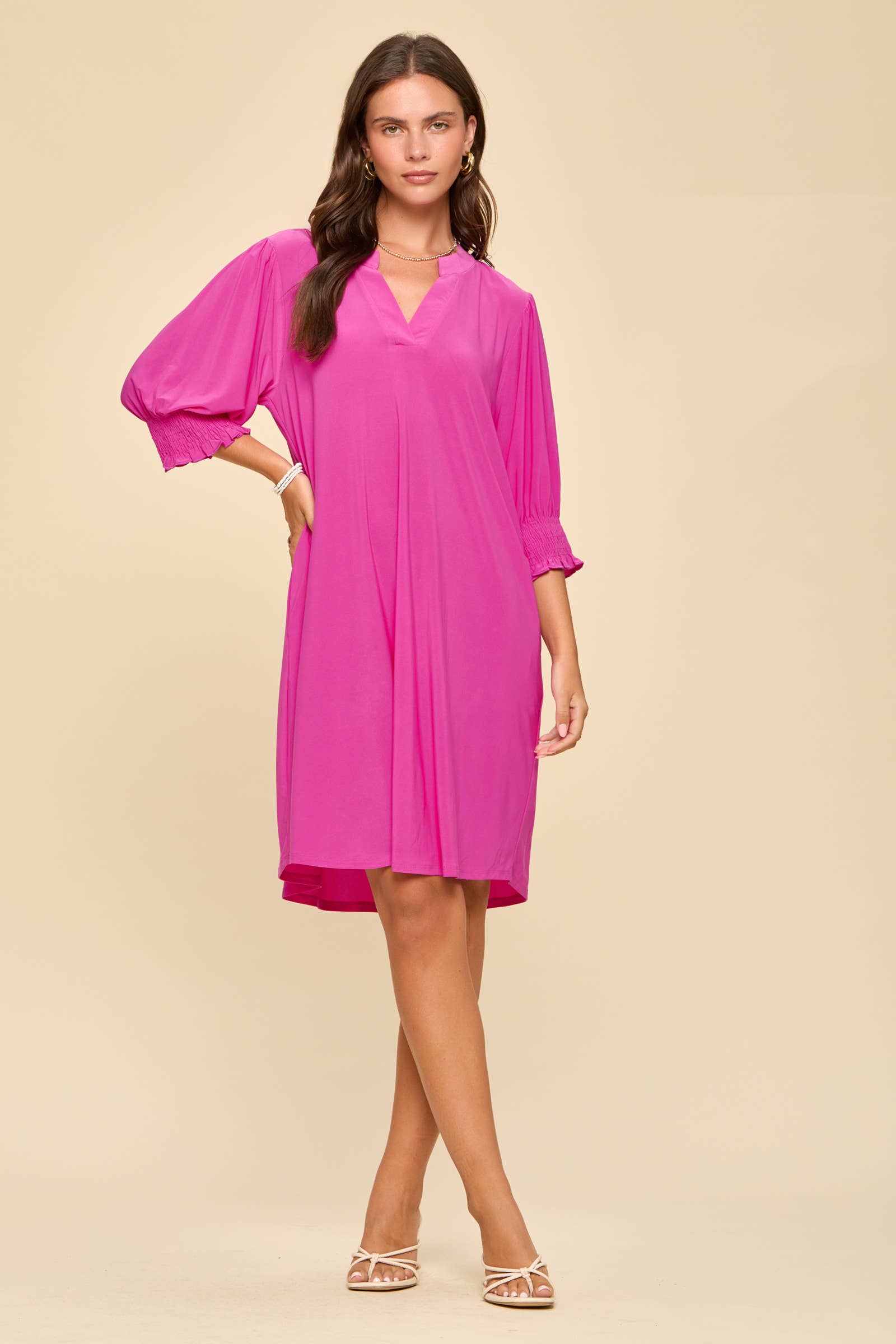 Woman wearing a bright pink dress on a beige background