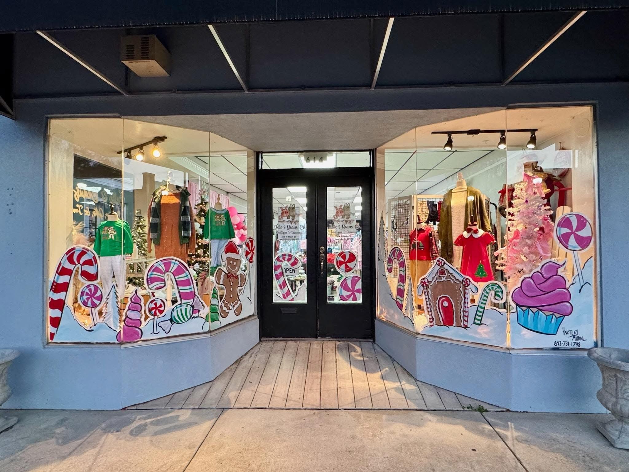 Storefront with festive window display featuring gingerbread men, candy canes, and other holiday-themed decorations.