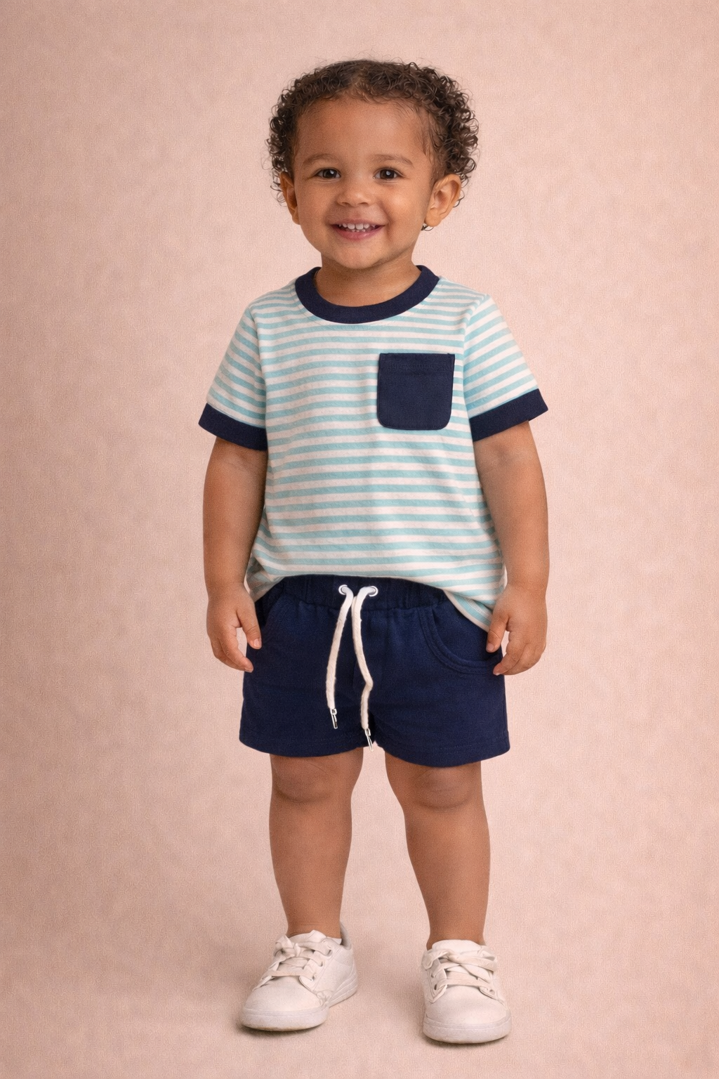 Child wearing a striped shirt and shorts on a pink background