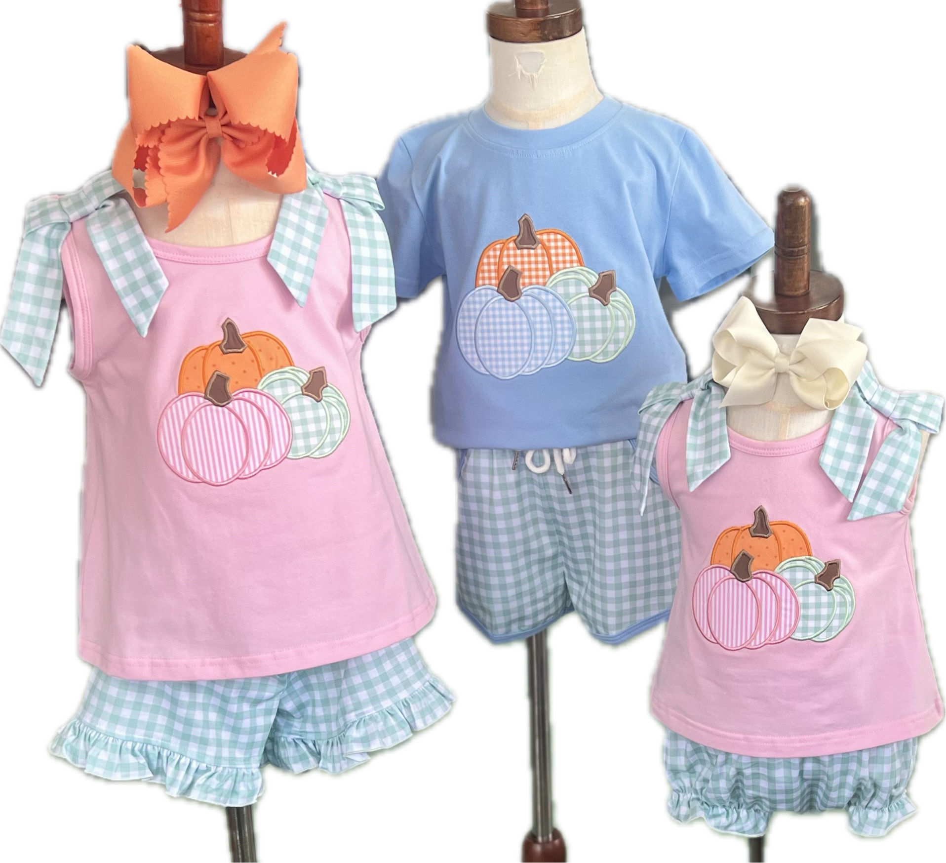 Children's clothing set with pink tank tops and blue shorts featuring pumpkins on mannequins.