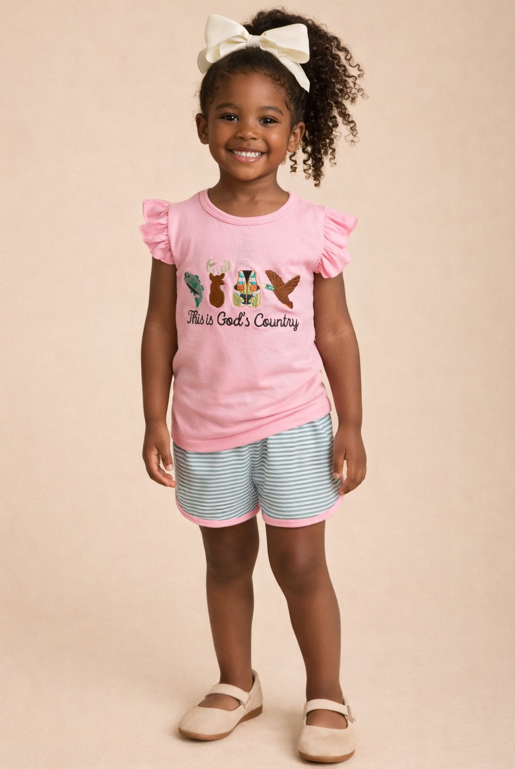 Young girl wearing a pink top with ruffled sleeves and striped shorts on a beige background