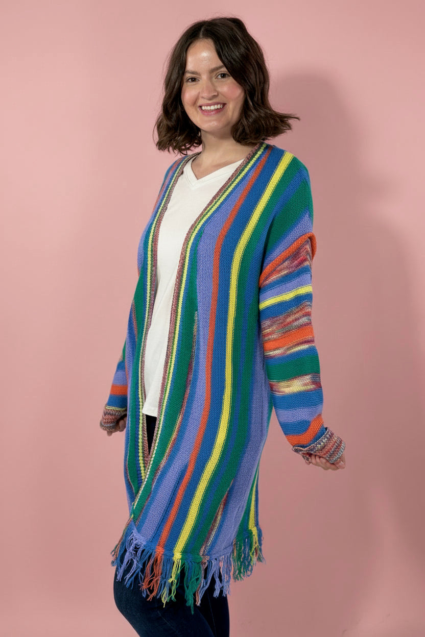 Woman wearing a colorful striped cardigan against a pink background