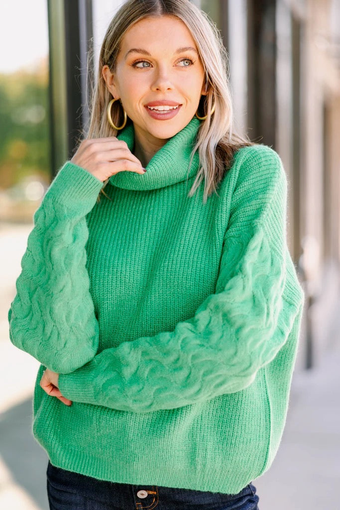Woman wearing a green cable knit sweater outdoors