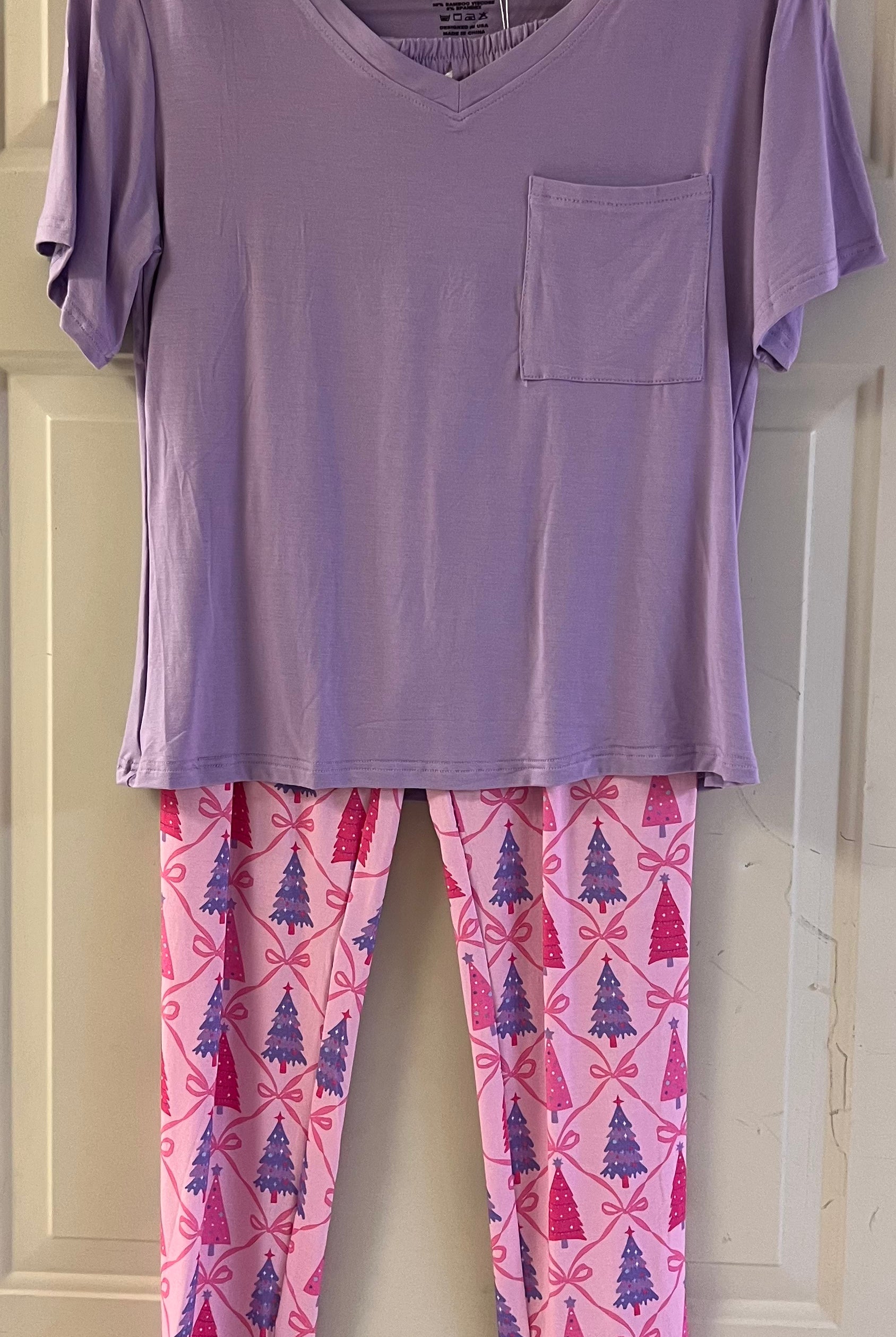 Lavender short-sleeve top with pocket paired with pink lounge pants featuring purple and magenta Christmas trees and bows.