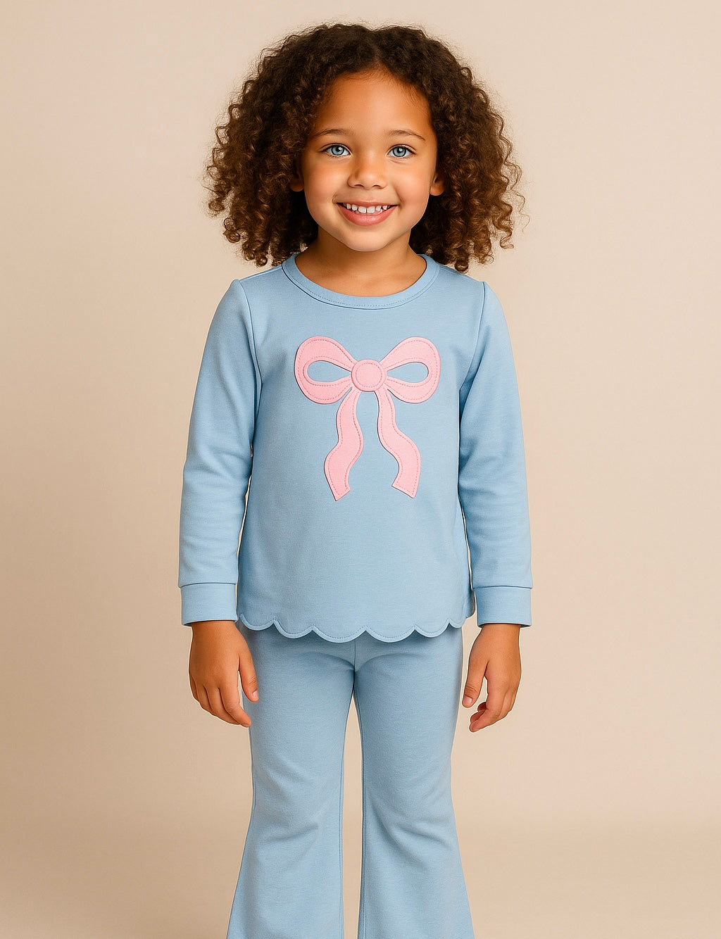 Child wearing a light blue outfit with a pink bow on a beige background
