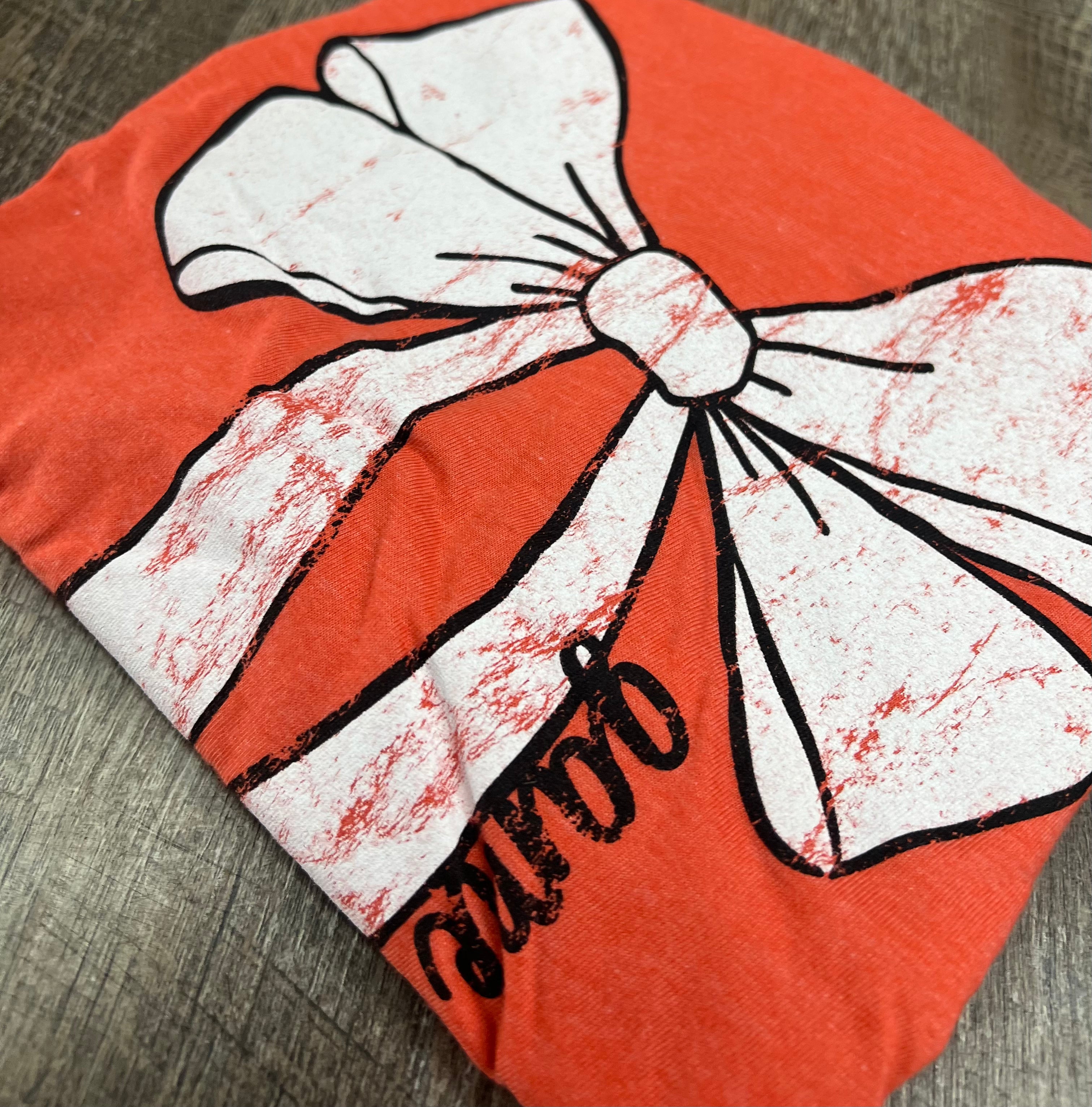 orange t-shirt with white bow outlined in black with game time written on the side of the bow
