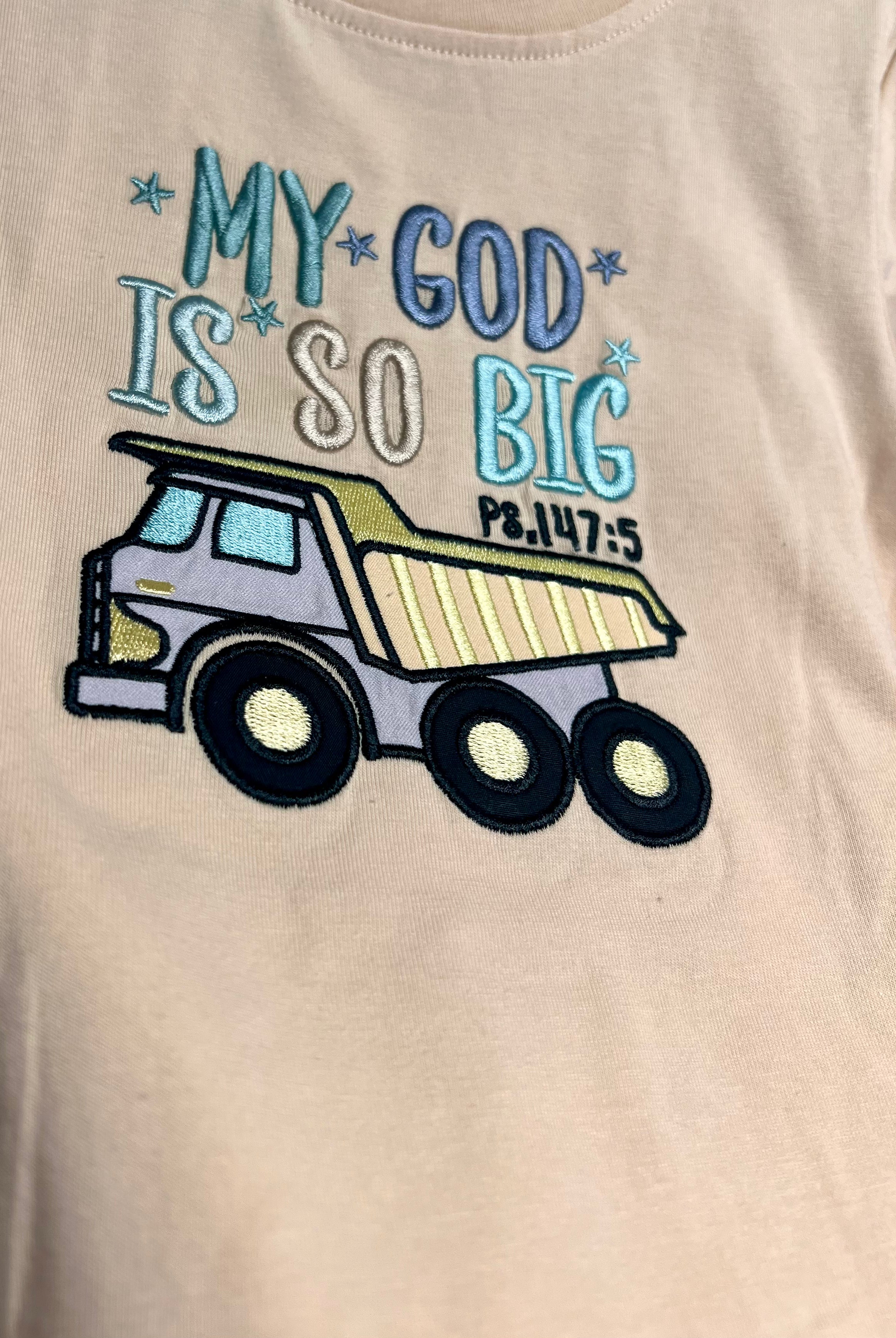 Beige t-shirt with a dump truck graphic and text 'My God is so big' on a beige background
