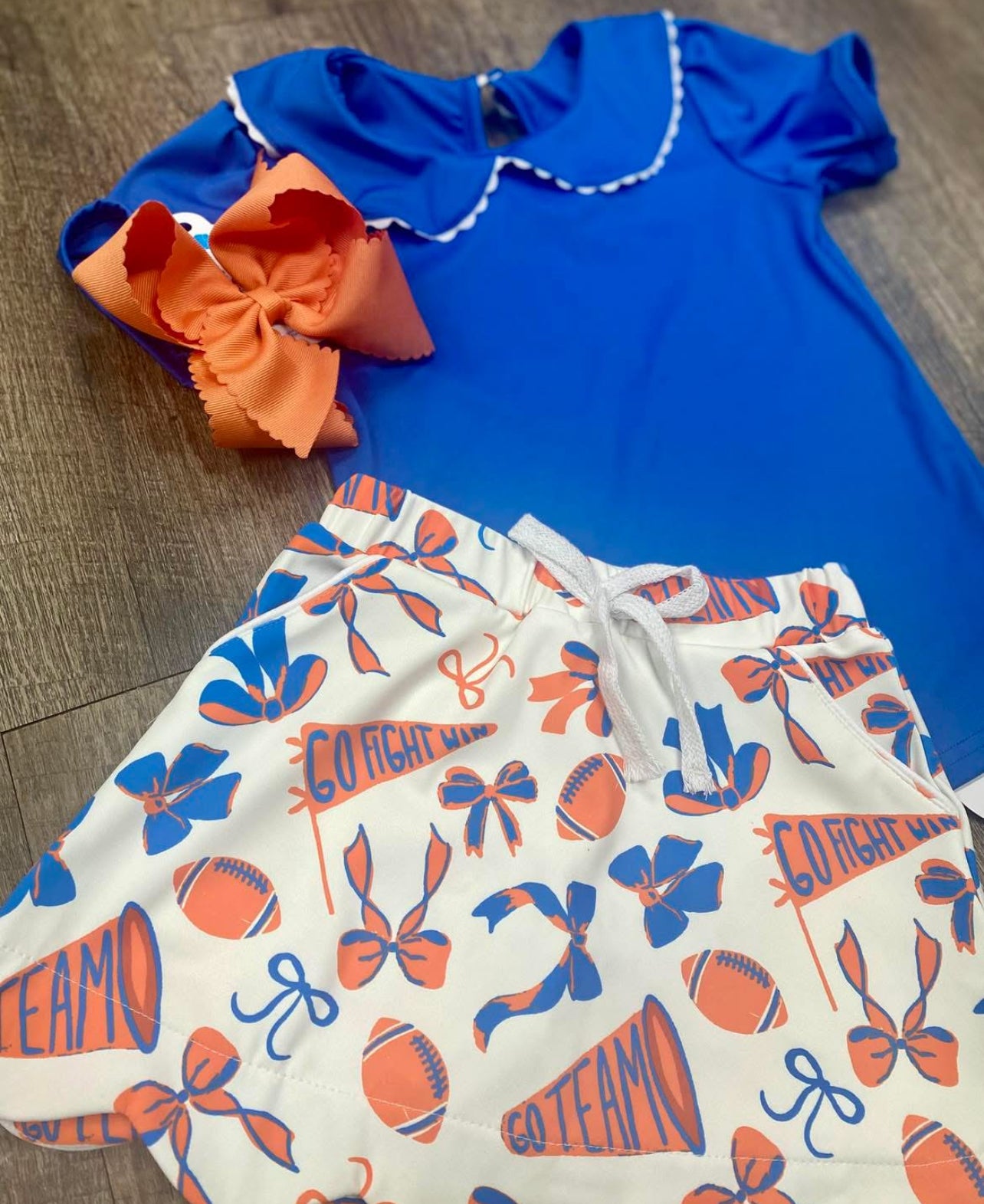 Blue collared top with blue and orange skort, "Go Fight Win" and "Go Team"