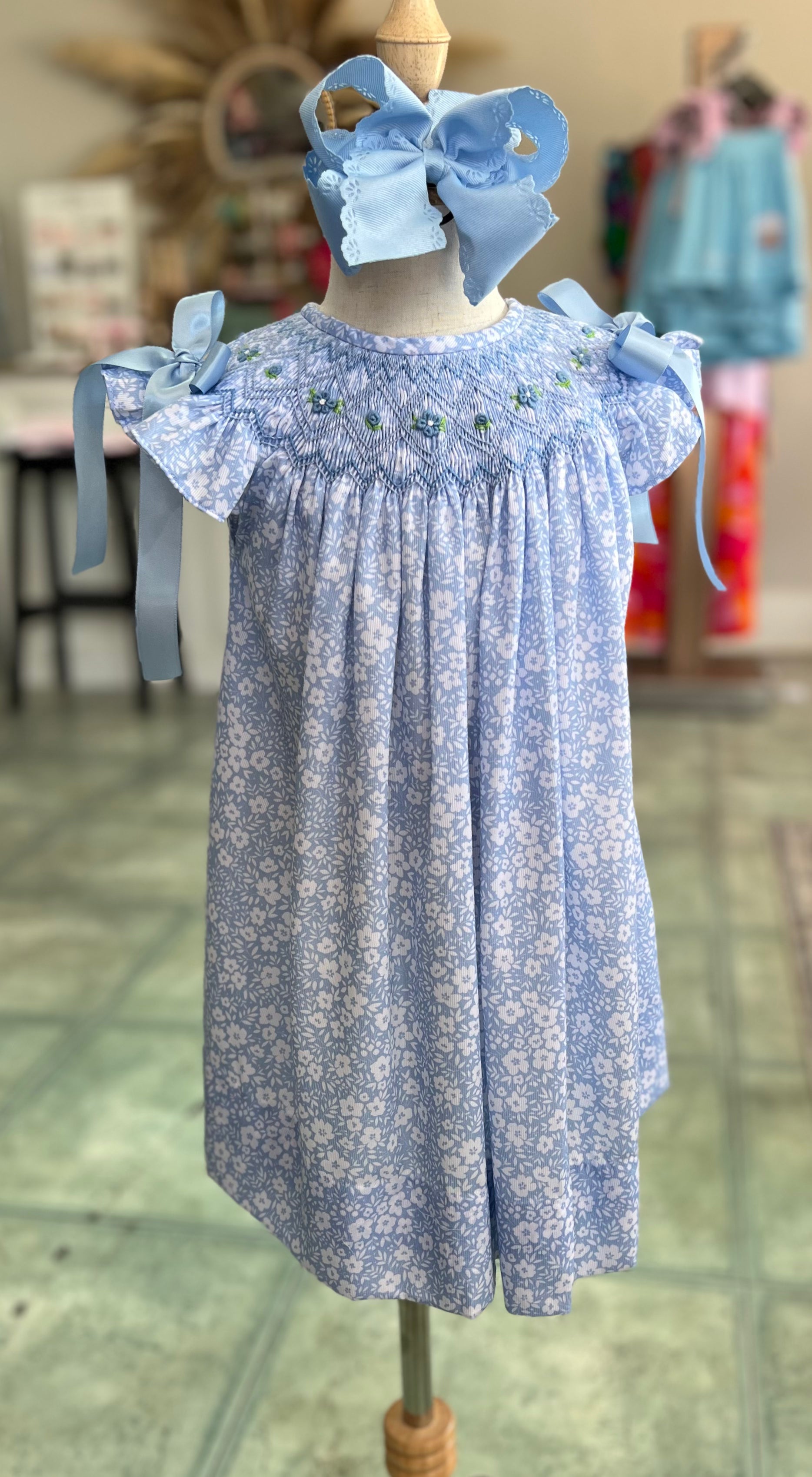Blue floral dress with matching headband on a mannequin against an indoor background