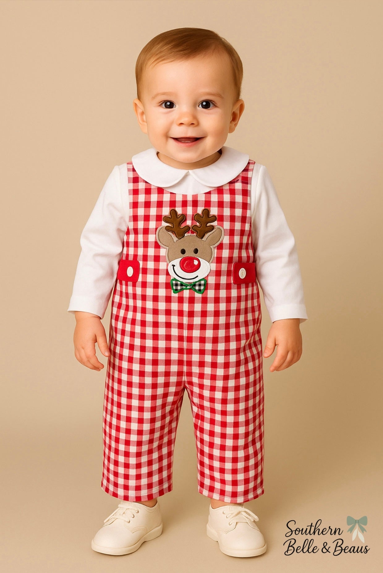 Baby wearing a red checkered outfit with a reindeer design on a beige background