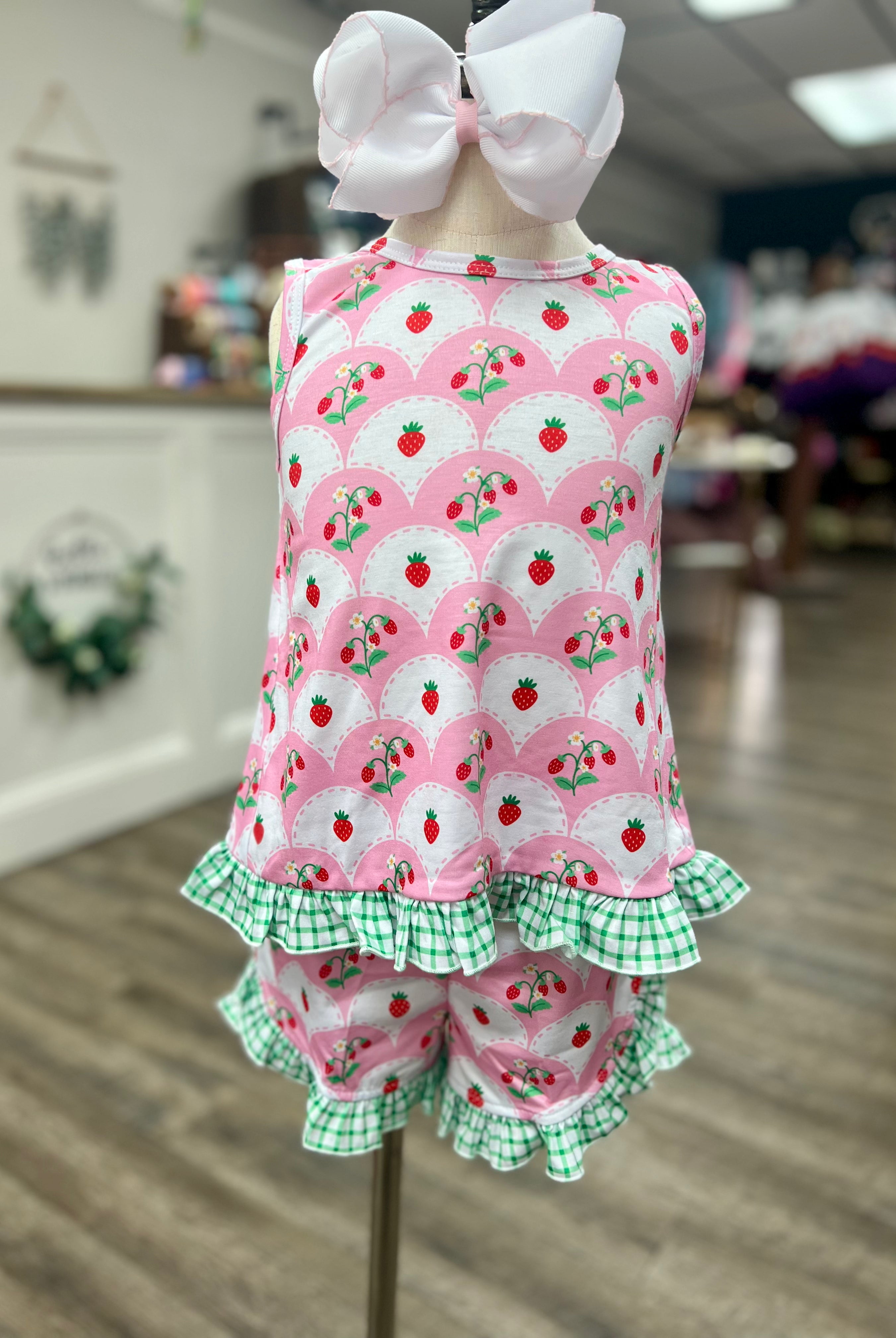 Children's outfit with pink floral and strawberry pattern on a mannequin.