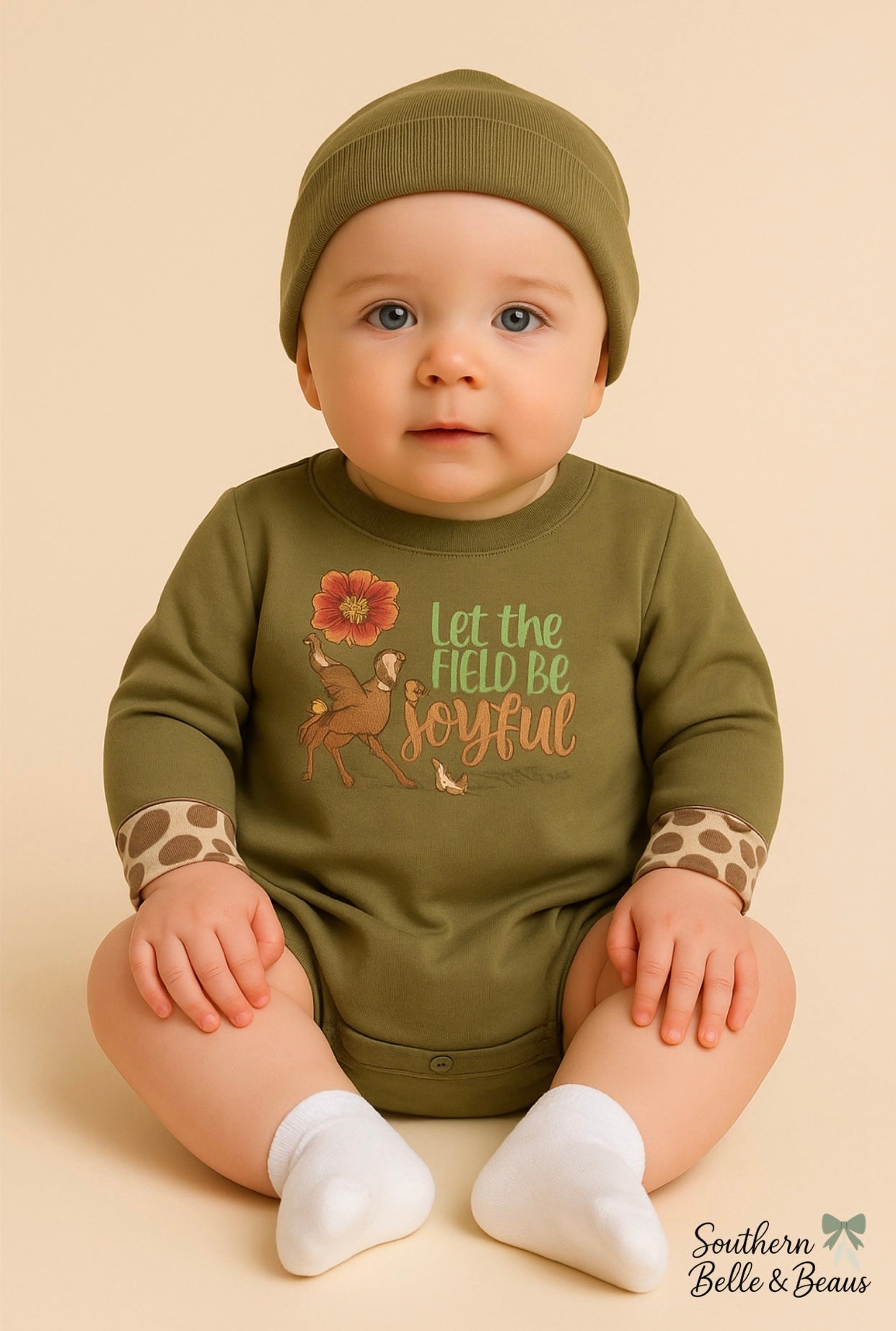 Baby wearing an olive green bubble with a turkey, deer, duck and text.