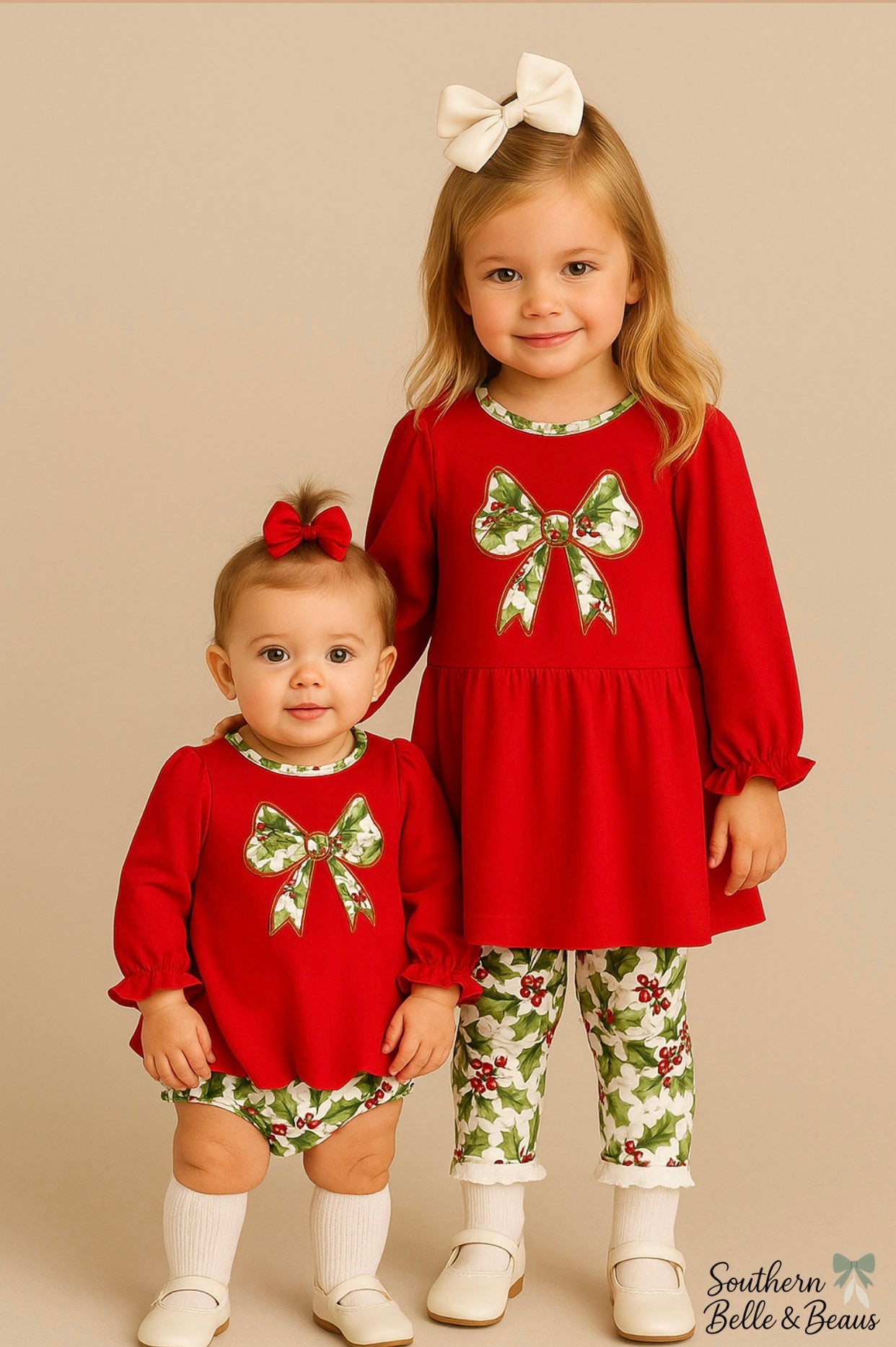 Two young girls wearing matching red outfits with floral patterns on a beige background.