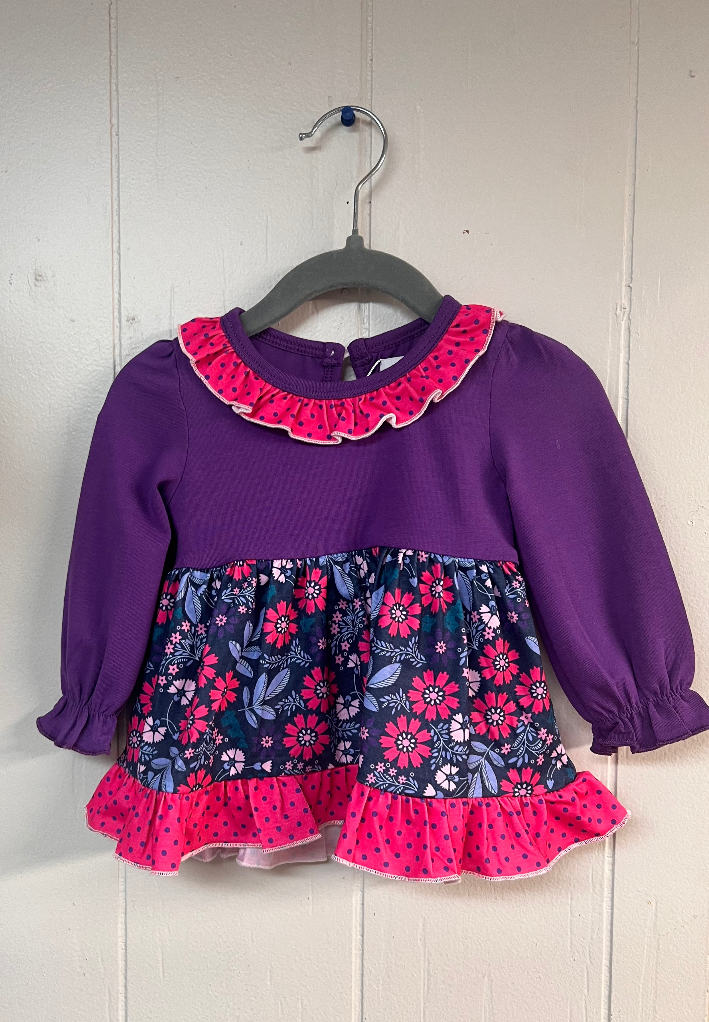 Purple long-sleeve baby diaper set top featuring a bright pink polka dot ruffle collar, floral purple and pink skirted layer, and matching pink ruffle hem.