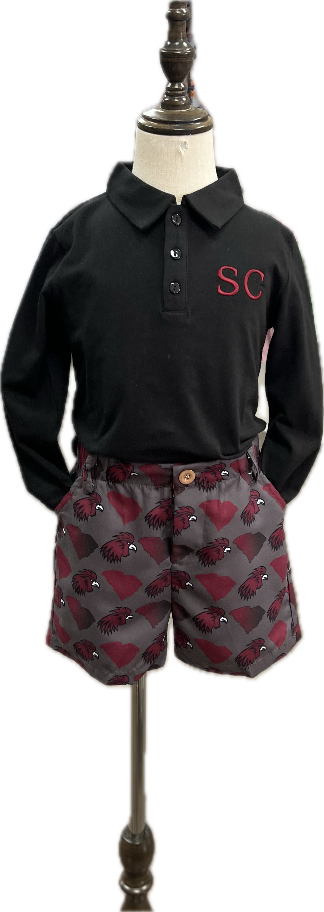 Black polo shirt with 'SC' logo and patterned shorts on a mannequin.