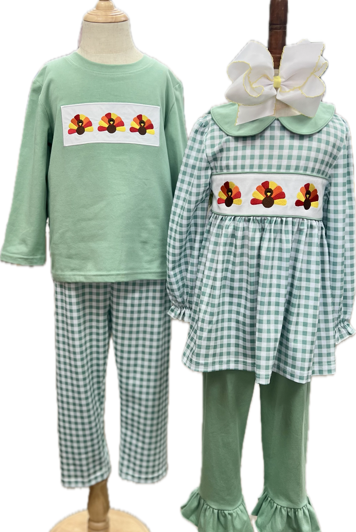 Children's green outfit with checkered pants and embroidered designs on a mannequin.