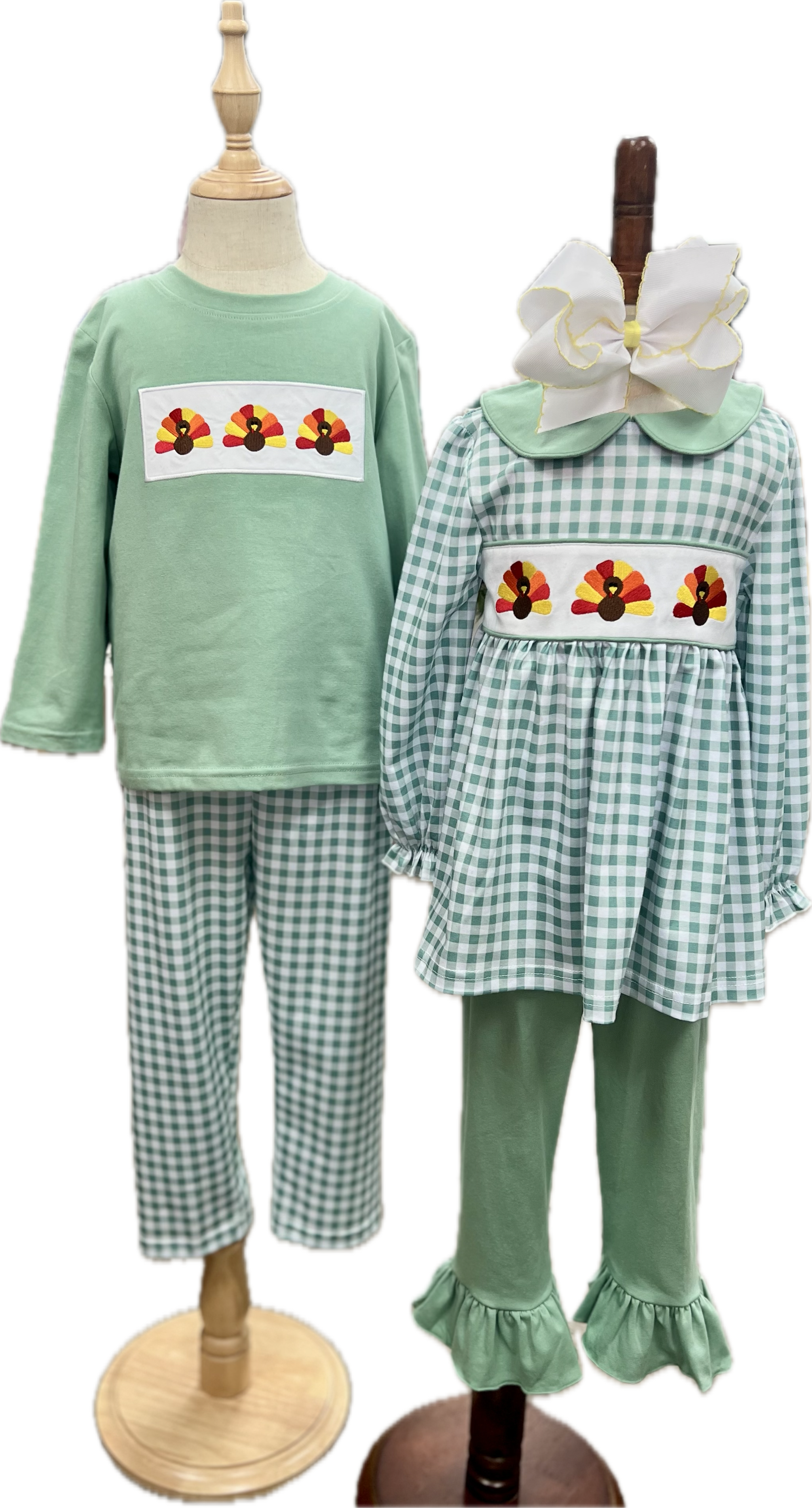 Children's green outfit with checkered pants and embroidered designs on a mannequin.