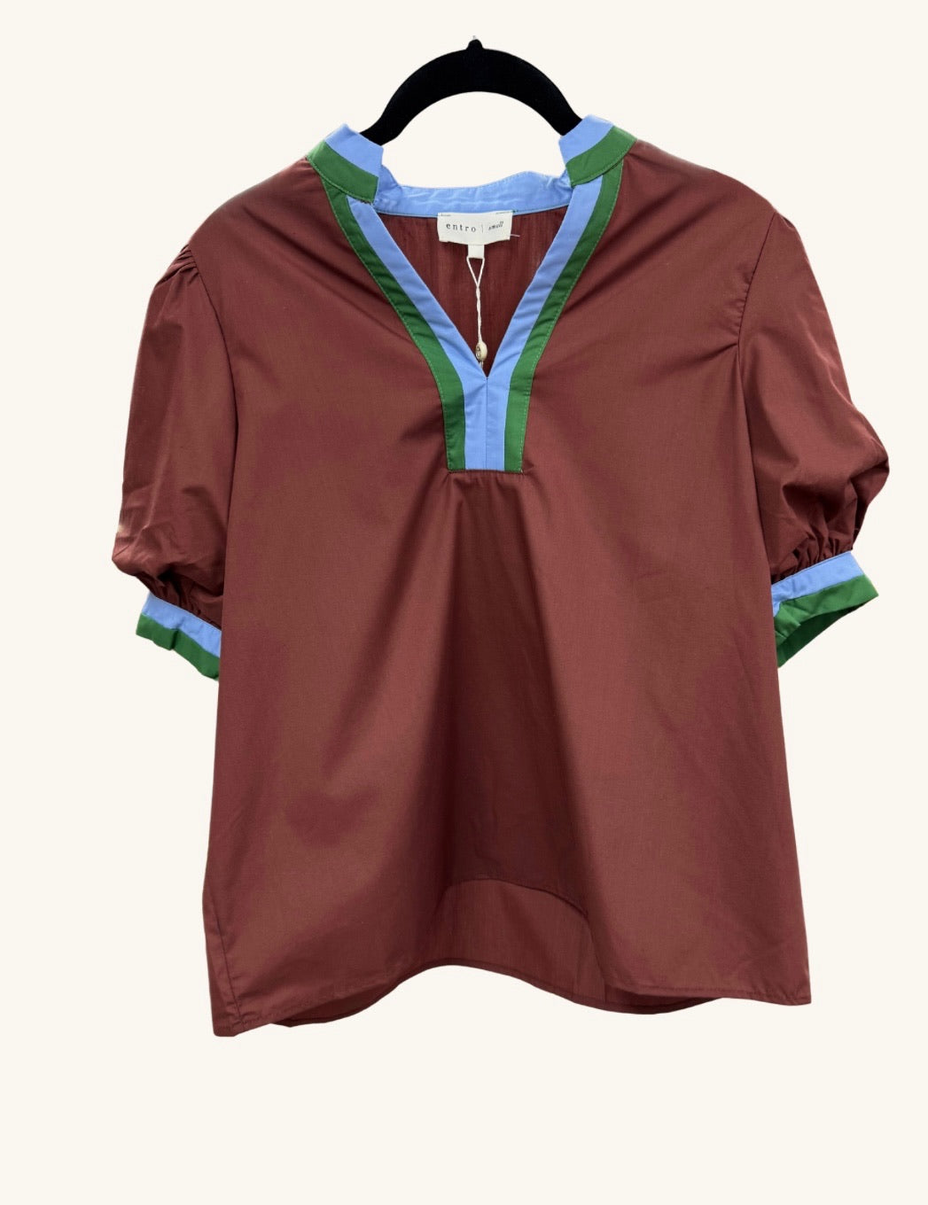 Rust-colored short-sleeve blouse with a split neckline, trimmed in contrasting blue and green accents, featuring a relaxed fit and gathered sleeve hems.