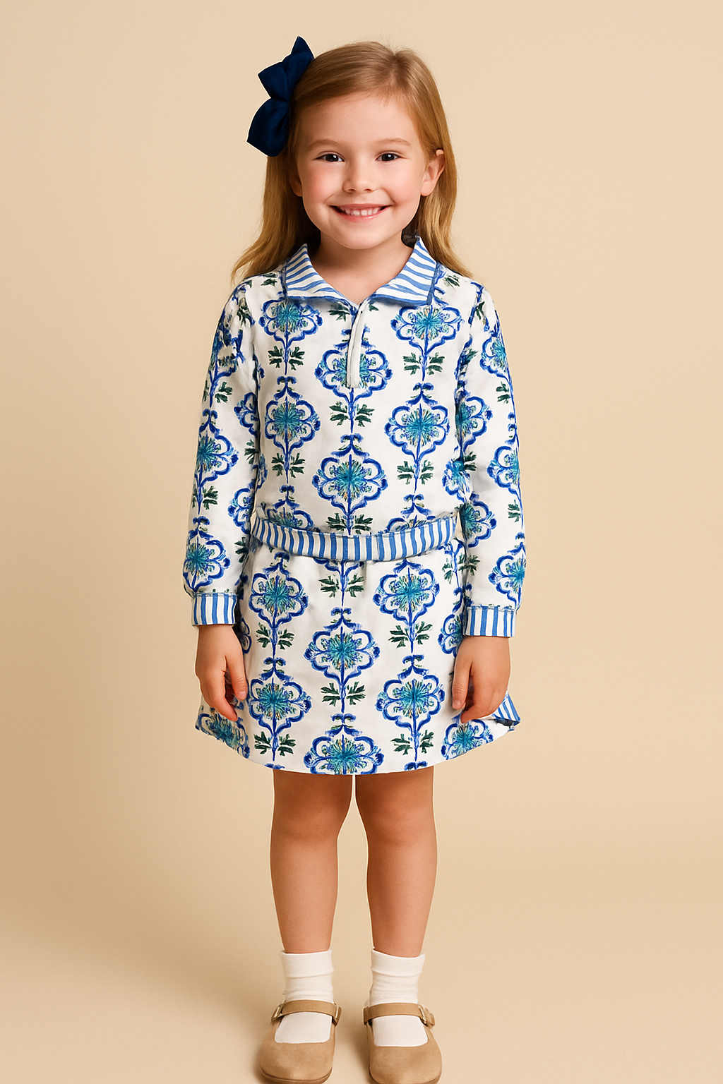 Girls blue floral two-piece set with striped trim — quarter-zip top and ruffle-waist skirt hanging on display.