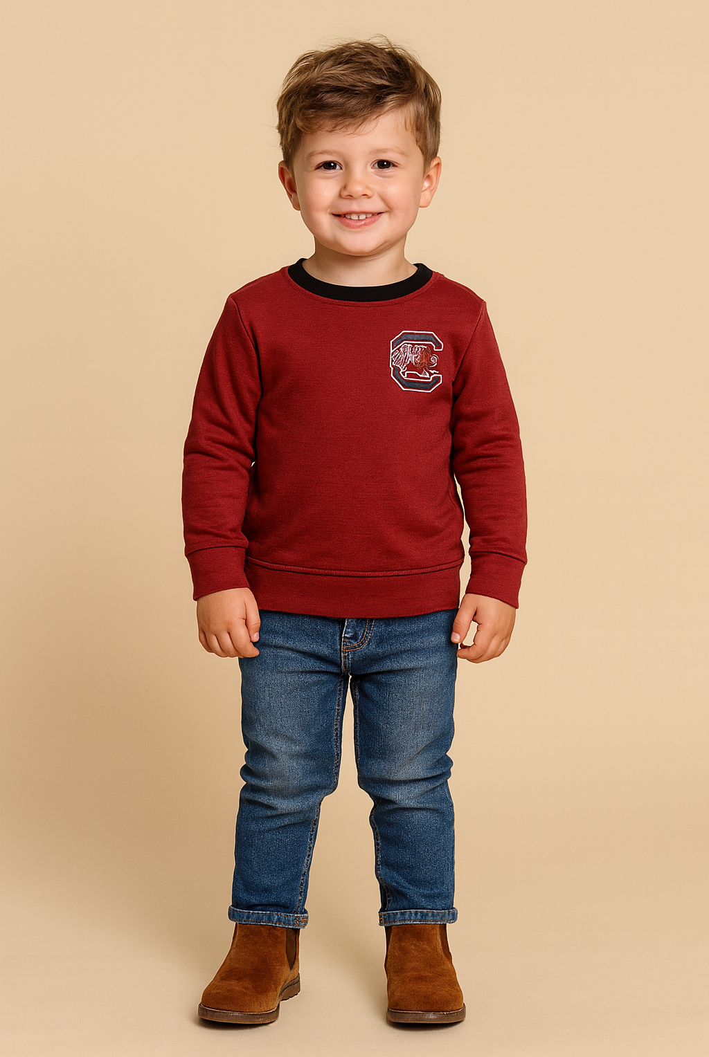 Child wearing a red sweatshirt with a logo, blue jeans, and brown boots on a beige background
