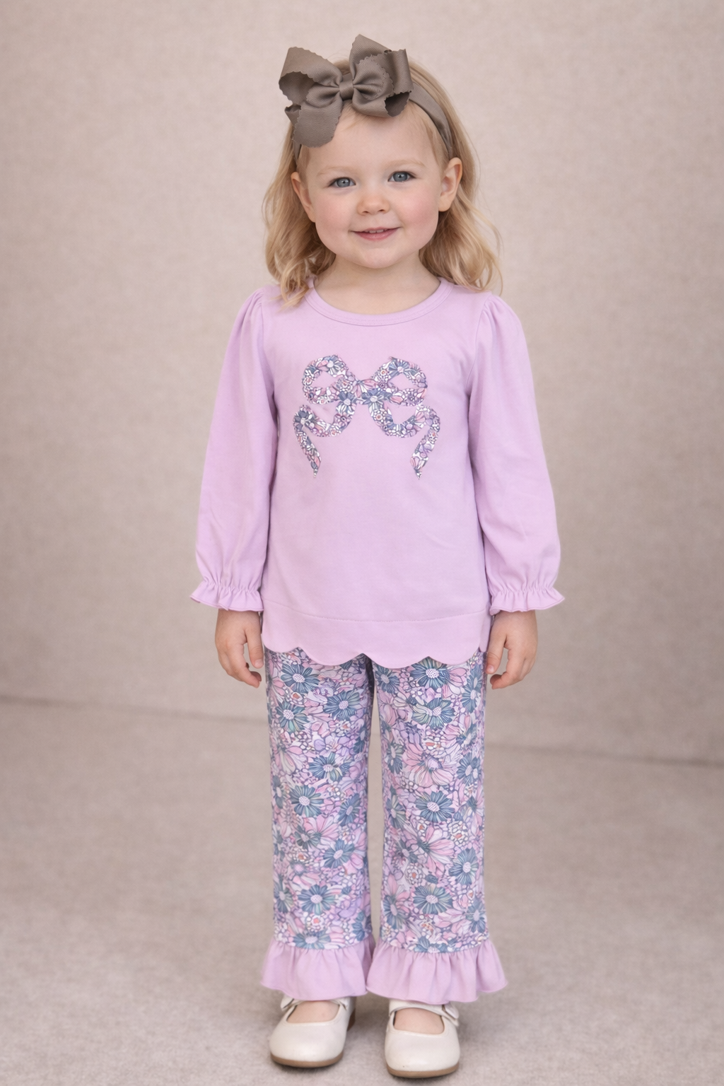Little girl wearing a lilac long sleeve shirt with a bow in the front.