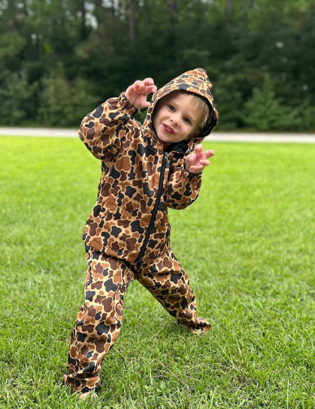 Child wearing a Camo print hunting suit outdoors on grass