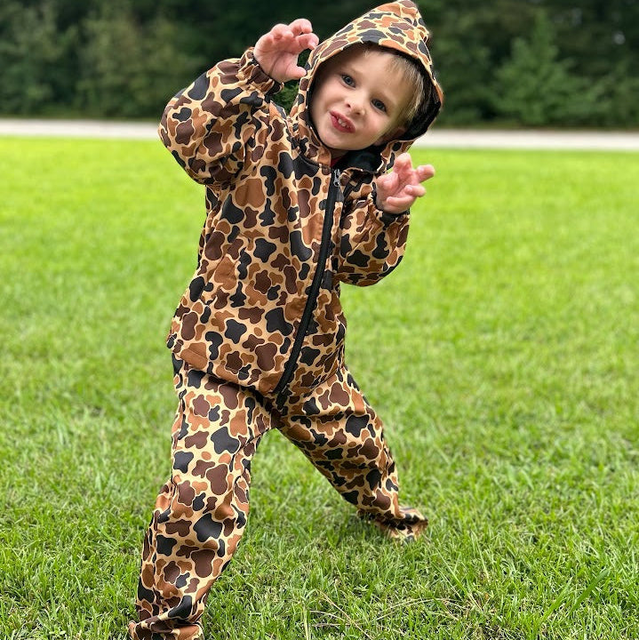 Child wearing a Camo print hunting suit outdoors on grass