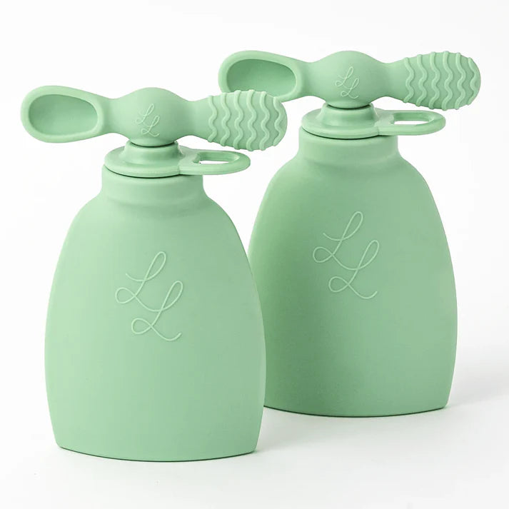 Two green silicone baby soothers on a white background