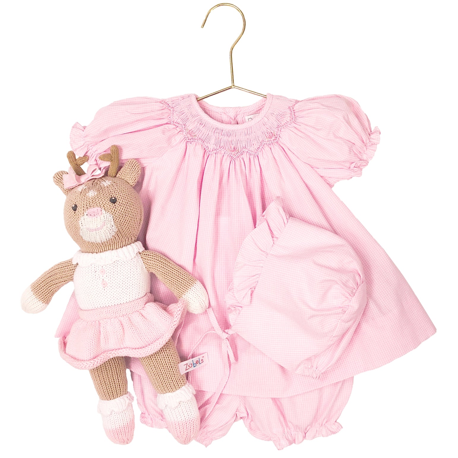 Pink baby dress with matching teddy bear on a hanger against a white background
