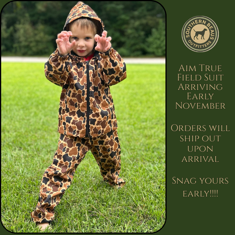 Child wearing a camo print hunting suit standing on grass with promotional text for Southern Belle Outfitters.