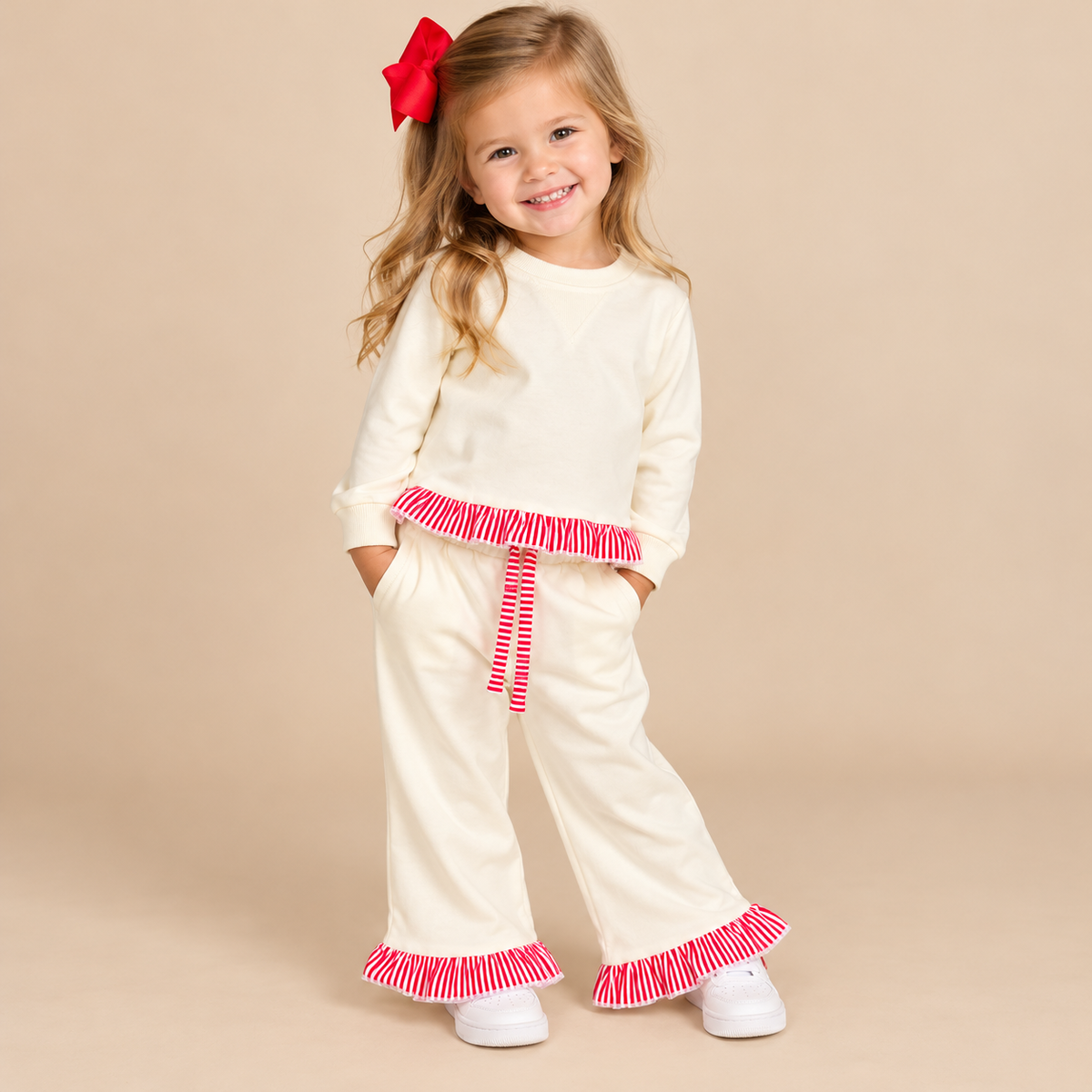 Toddler girl wearing a longsleeve sweatsuit with red & white trim on the bottom of the shirt and pants.