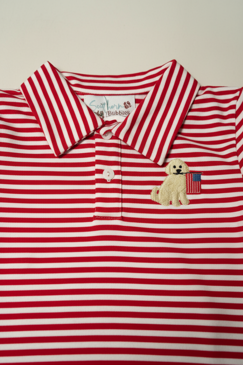 Close-up of embroidered golden retriever holding American flag on red stripe boys polo