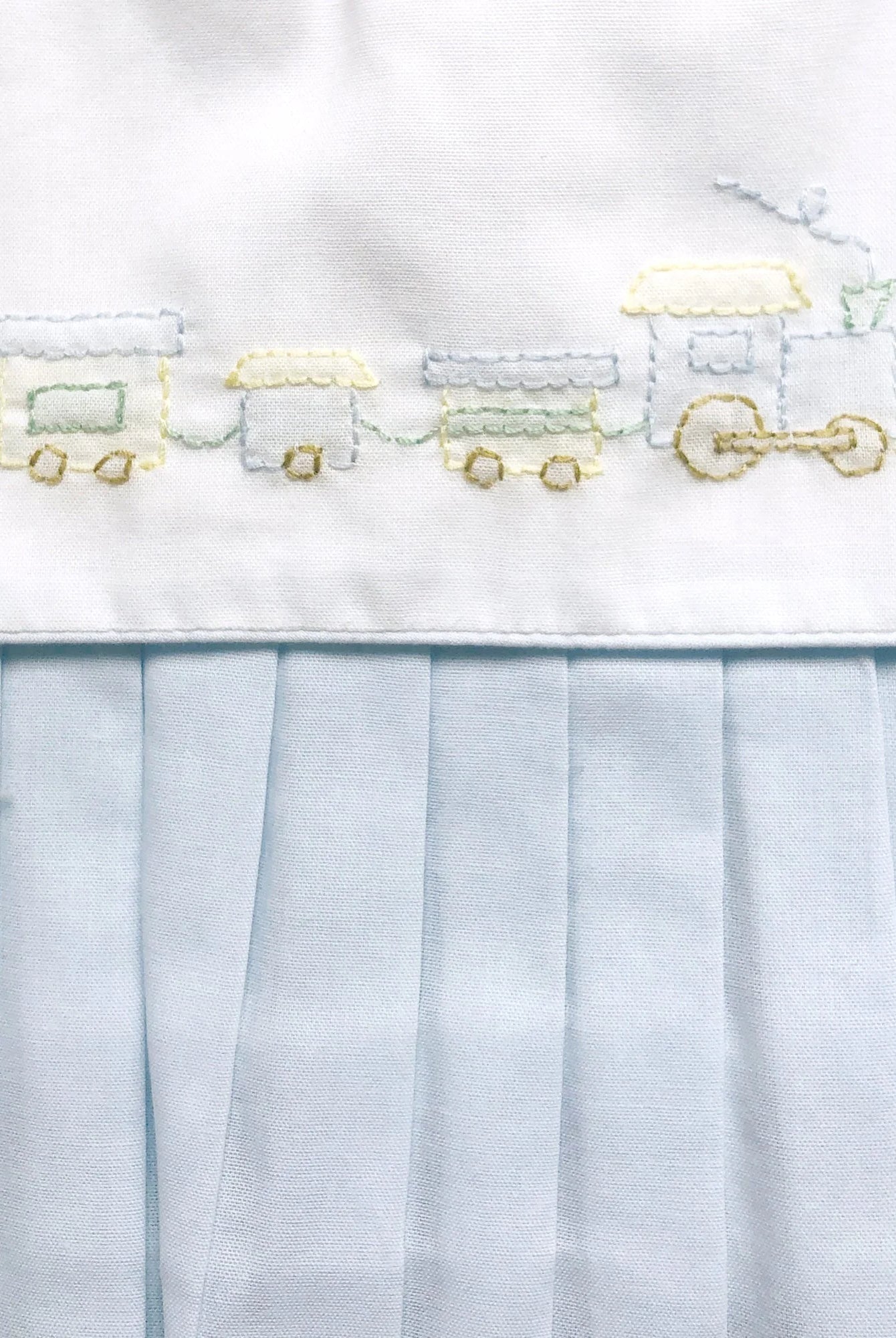 Embroidered train design on a white fabric with a light blue tulle overlay.