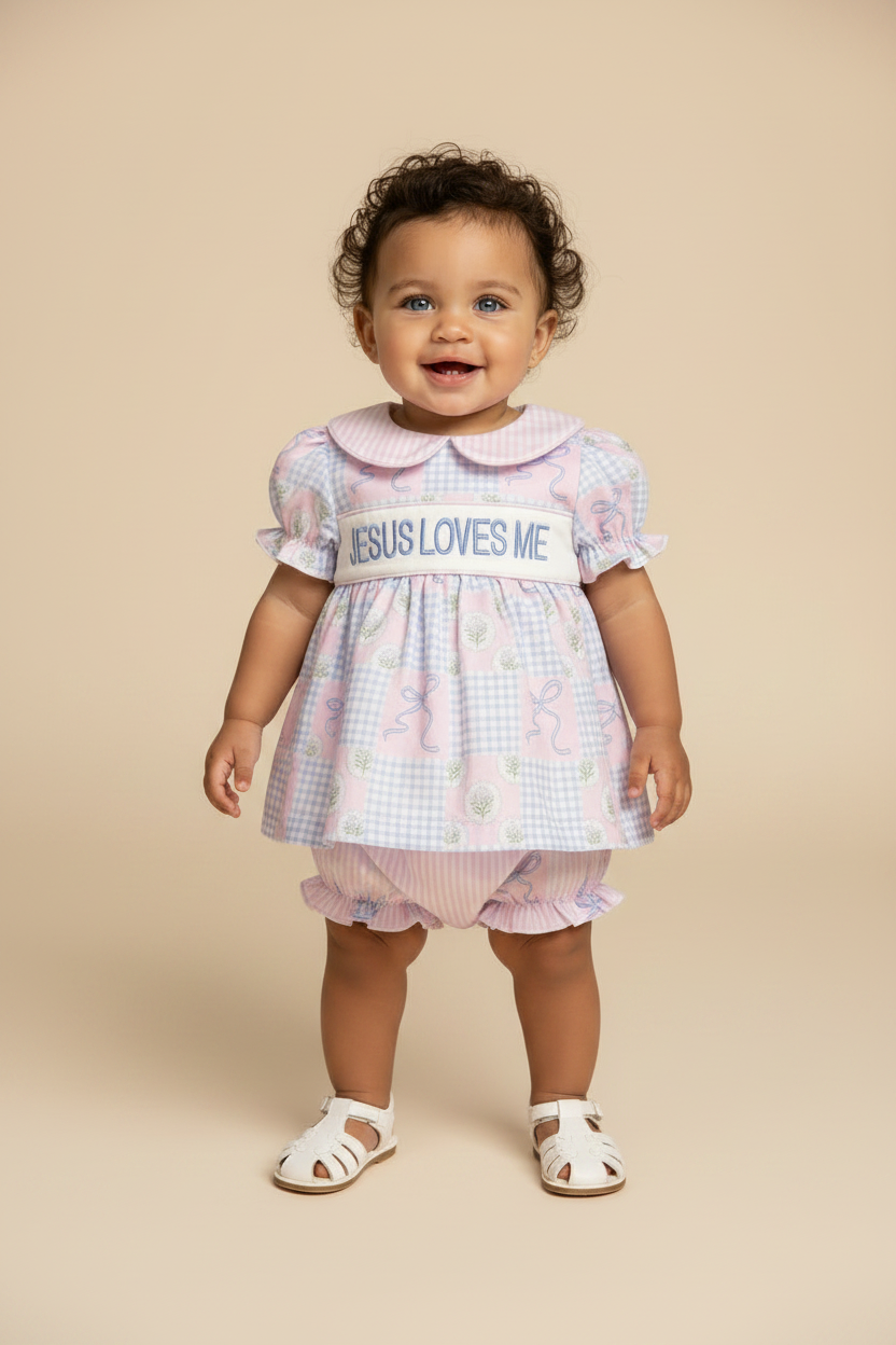 Baby girl standing with a Jesus Loves Me outfit.