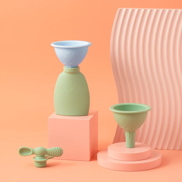 Set of funnels on pink and peach-colored stands with a pink textured vase in the background.