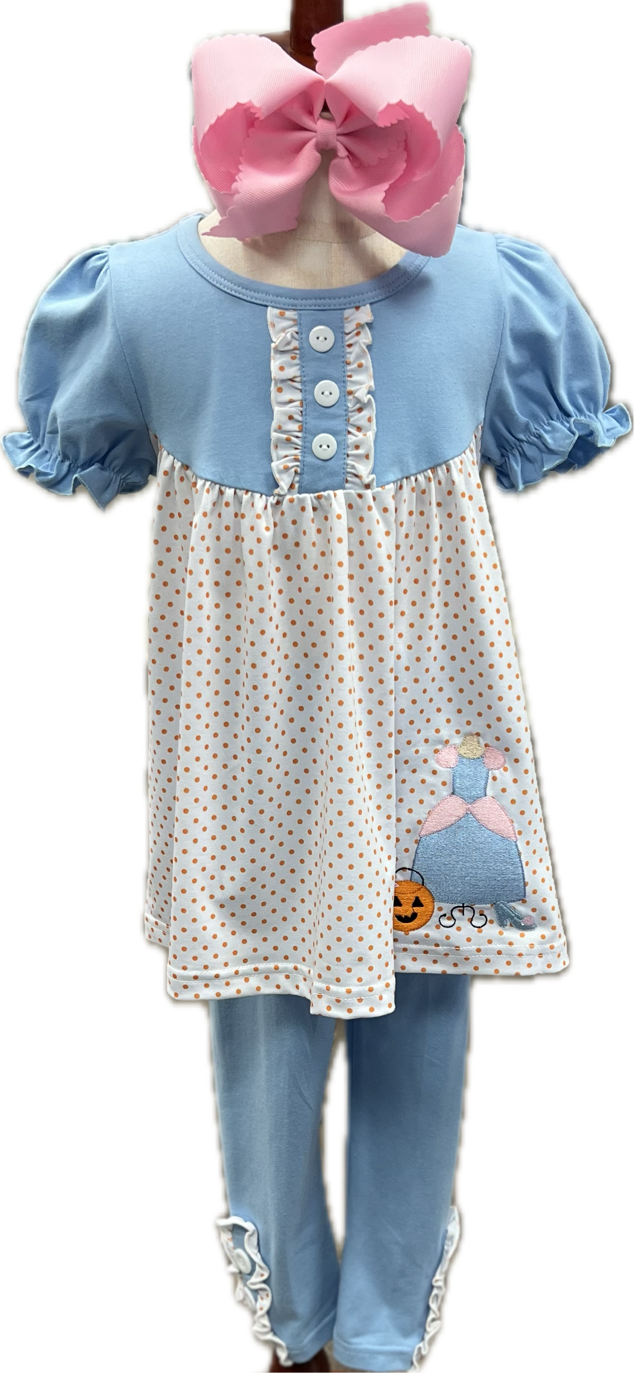 Children's outfit with polka dot dress, blue pants, and pink bow on a white background