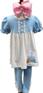 Children's outfit with polka dot dress, blue pants, and pink bow on a white background