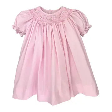 Pink dress with smocked details on a white background
