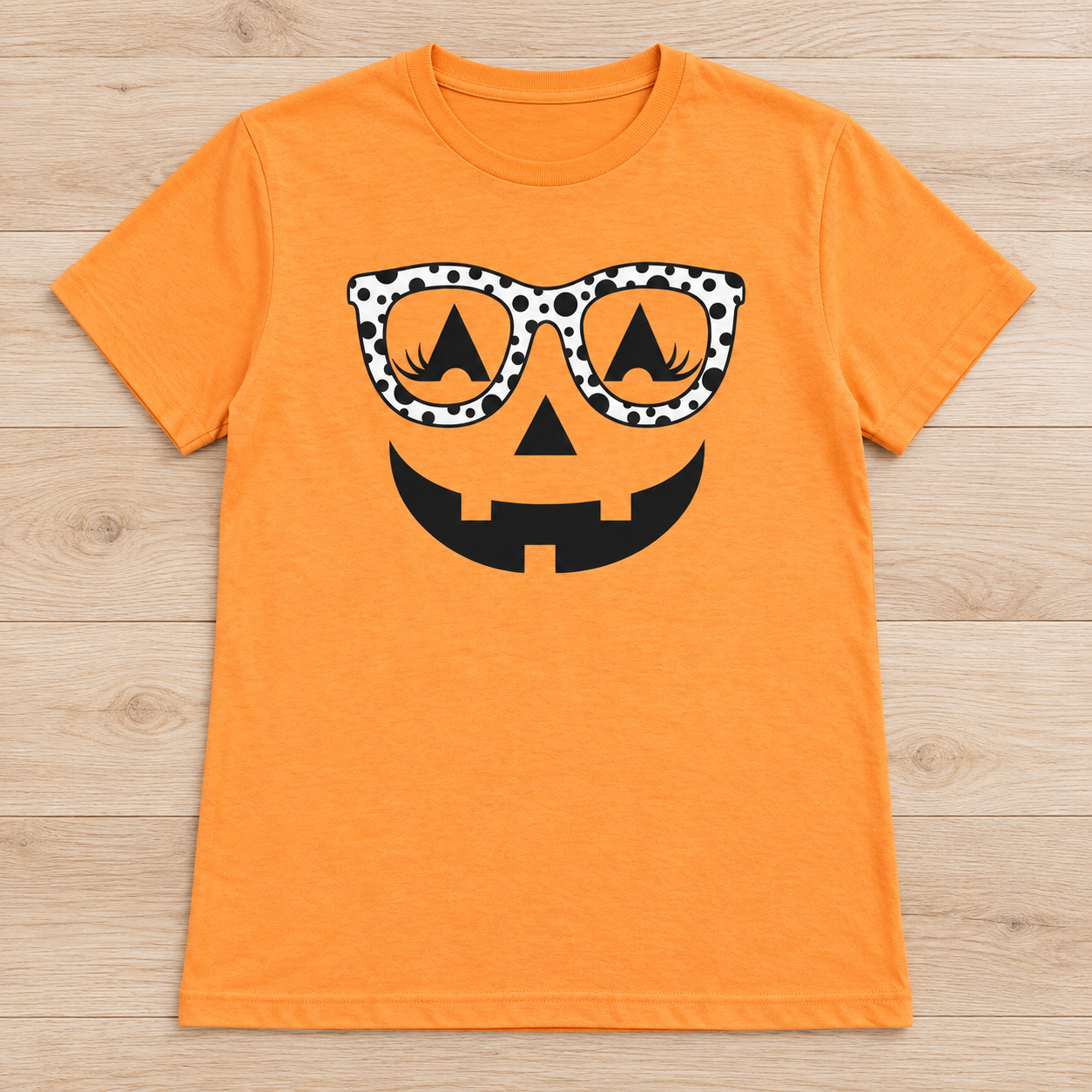 Orange short-sleeve tee with a black jack-o’-lantern face wearing black-and-white polka-dot glasses