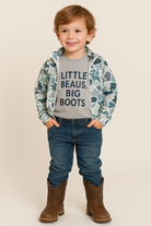 Child wearing a patterned jacket, gray shirt with text, blue jeans, and brown boots on a beige background

