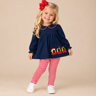 Toddler girl wearing a navy peter pan collard shirt with red and white striped pants.