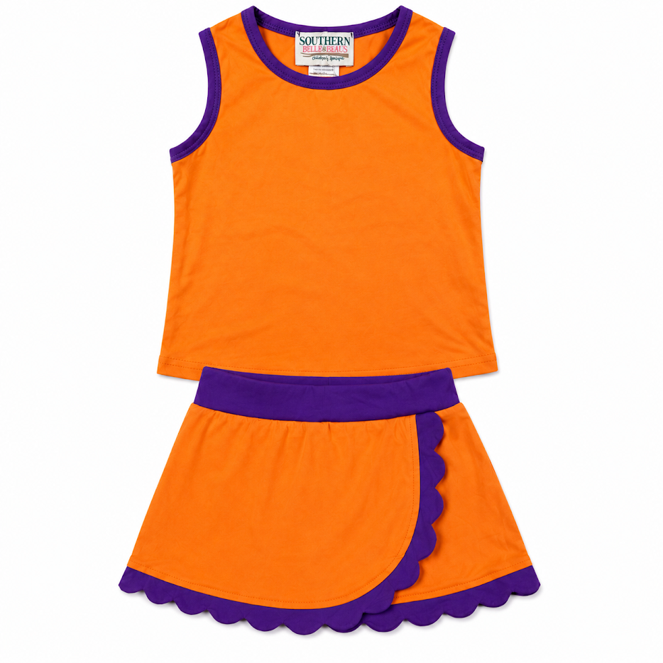 A two-piece girls' outfit set featuring a bright orange sleeveless tank top and matching skater skirt with purple trim, a purple waistband, and scalloped edges, displayed on a clean white background.