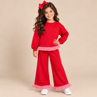 Young girl wearing a red pant suit with red & white trim.